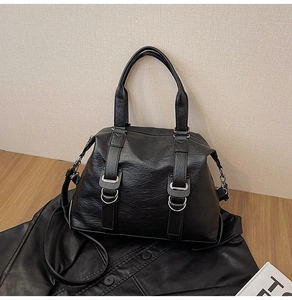 Close-up of black lychee grain leather tote bag with silver hardware on vintage desktop