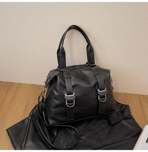 Detail of black textured leather Boston bag with silver hardware and dual handles