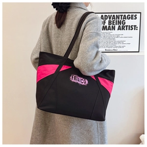 Detail of large black and pink canvas tote bag with FRIAICG logo worn by a model