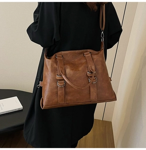 Detail shot of a brown vintage leather tote bag showing texture and adjustable shoulder strap