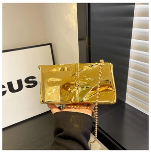 Detalle del bolso de fiesta dorado con diseño plisado y cadena de cuentas metálicas