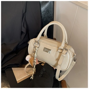 Detail of a creamy white patent leather bowling bag with silver hardware and baseball charm