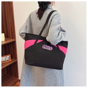 Detail view of large black canvas tote bag with pink contrast panels and shoulder straps