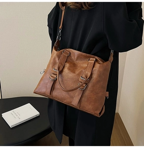 Close-up of vintage brown leather tote bag with metallic ring buckle and shoulder strap