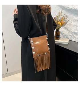 Detail of caramel brown bucket bag featuring metallic rivets and long tassel fringe