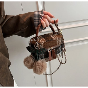 Detail van de geruite wollen box-tas met kersenhanger en metalen ketting