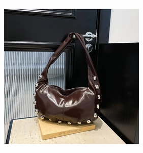 Close-up of shiny dark coffee oil wax leather underarm bag with bold silver stud details