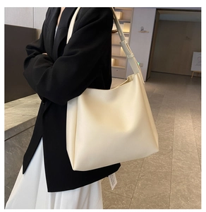 Minimalistische crèmewitte leren tote bag gedragen over de schouder door een model