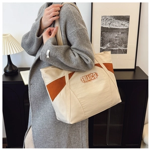Detail of color-block canvas tote bag with caramel trim and artistic FRIAICG lettering