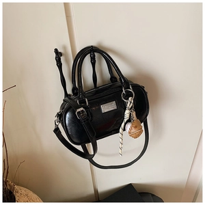 Detail view of a black glossy bowling bag featuring retro textures and a baseball charm