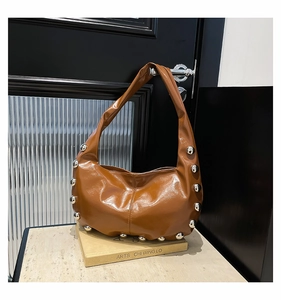 Detail view of brown hobo bag featuring silver rivets and polished oil wax leather