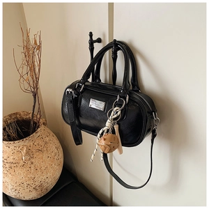 Close-up of black glossy bowling bag with silver plaque, strap, and creative charm