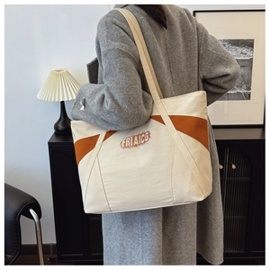 Close-up of contrast color canvas tote bag worn by a model in a minimalist room