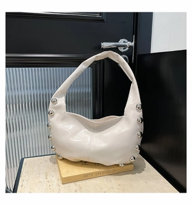 Detailed view of cream hobo bag with bold silver studs on yellow art book