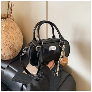Detail of glossy black Boston bowling bag featuring vintage textured leather and silk scarf