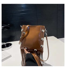 Detail of a brown fringe bucket bag featuring silver studs and long leather tassels