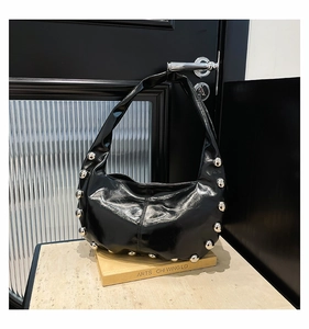 Detail of silver rivets on black glossy faux leather hobo bag hanging on a door handle