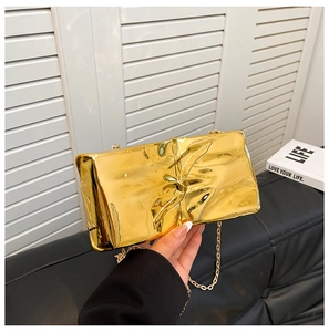 Detalle del bolso de mano dorado metalizado con diseño plisado y cadena fina
