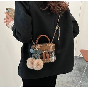 Sac bandoulière à carreaux marron avec poignée en cuir et pompon pelucheux sur le mannequin