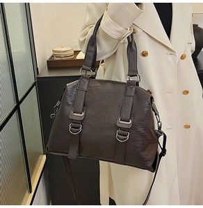 Detail of dark brown leather tote bag with silver hardware on a trench coat model