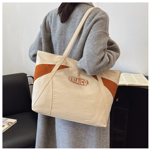 Close-up of color-block canvas tote bag with FRIAICG print and orange-brown leather accents