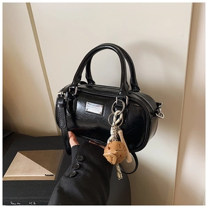 Detail shot of black glossy bowling bag with silver hardware and brown leather charm