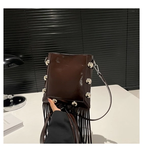 Detail of dark brown bucket bag with silver studs and long leather fringes