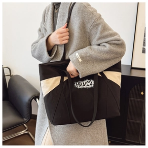Detailed view of a large black and cream canvas tote bag worn on a model's shoulder