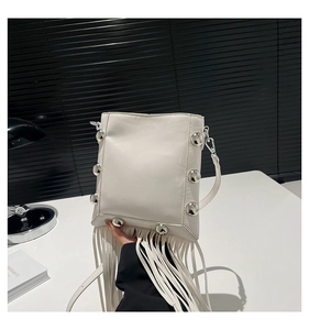 Detailed shot of white leather crossbody bag with silver studs and long fringe tassels