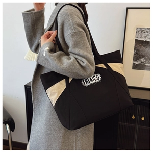 Close-up of contrast beige side panels and vintage lettering on the black canvas tote bag