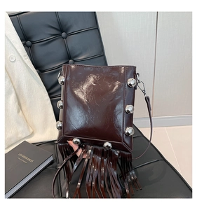 Detail of dark brown glossy bucket bag with silver stud rivets and long leather tassels