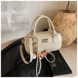 Detailed view of cream PU leather bowling bag with silver plaque and trendy keychain charm