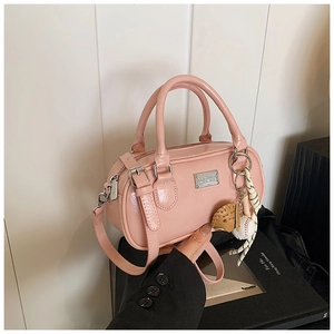 Pink patent leather Boston bag detail featuring round handles and baseball glove charm