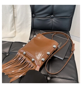 Detail of brown leather fringe bag featuring large silver stud accents and glossy finish