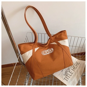 Close-up of a caramel canvas tote bag with white contrast panel and logo in a metal basket