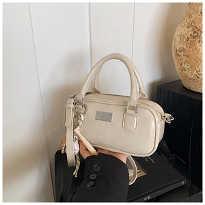 Detail of cream white mini bowling bag with baseball charm and polished leather texture