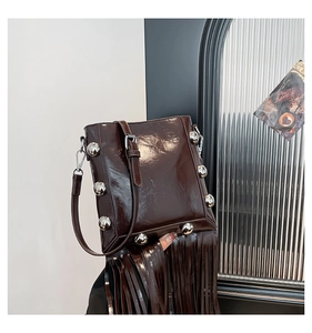 Detail of dark brown leather bucket bag with silver studs and long fringe tassels