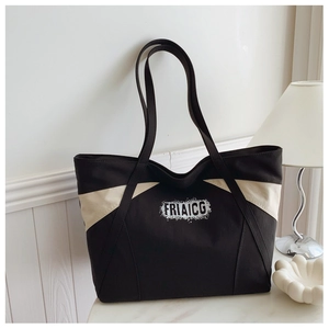 Detail of contrast canvas tote bag featuring black and beige patchwork with FRIAICG logo