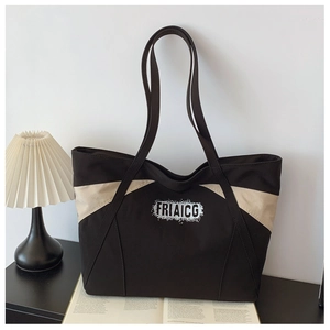 Detail of contrast stitching on a large black canvas tote bag with FRIAICG logo