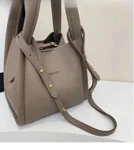 Detail of taupe lychee leather bucket bag showing adjustable strap and gold rivets