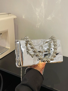 Bolso de noche de acrílico espejo plateado con asa de cuentas gruesas en vista de mano