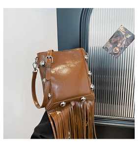 Detail of caramel brown glossy tassel crossbody bag with silver rivet studs and long fringe
