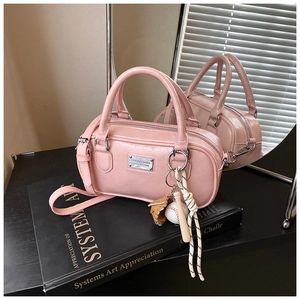 Detailed macro view of pink Boston bag with silver plaque and sports charm on books