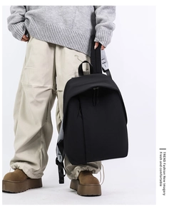 Close-up of minimalist black nylon backpack with a reinforced top handle and wide straps