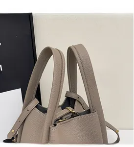 Close-up of taupe litchi grain leather bucket bag with reinforced handles and gold hardware