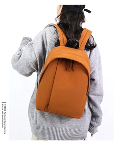 Detail view of ginger orange backpack showing water-resistant nylon fabric and zippers