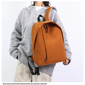 Detail of the wide shoulder strap on the orange canvas backpack for better comfort