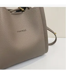 Detail shot of pebbled leather texture and embossed logo on taupe bucket bag