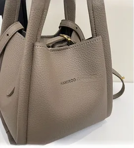 Close-up of litchi grain leather bucket bag with gold hardware and side strap detail