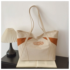 Detail of canvas tote bag showing side color-block design and brand lettering